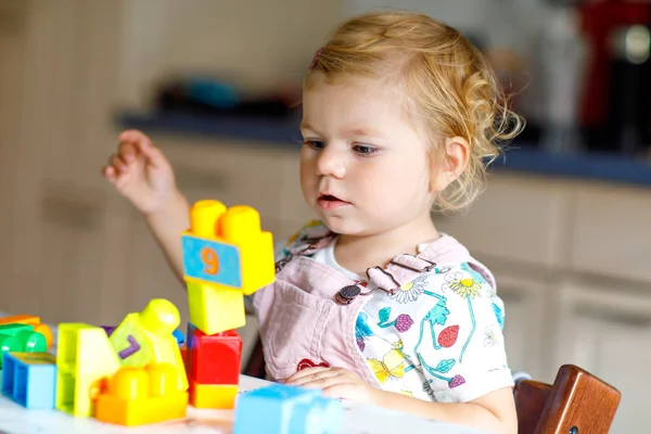 Förtjusande liten flicka leker med pedagogiska leksaker i barnkammaren. Glad frisk barn att ha kul med färgglada olika plastblock hemma. Söt baby lärande skapa och bygga. — Stockfoto