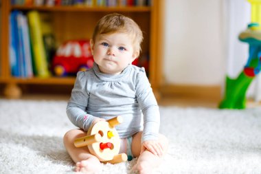 Eğitici oyuncaklarla oynayan sevimli bir kız bebek. Mutlu sağlıklı çocuk evde renkli tahta oyuncaklarla eğleniyor. Doğa oyuncağı olan çocuklar için erken gelişim.