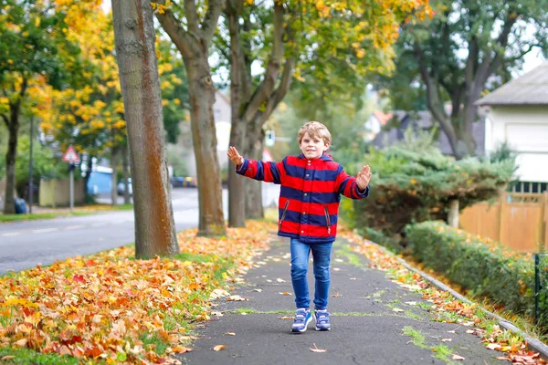 Menino feliz correndo na rua outonal depois da escola. Miúdo feliz com as férias escolares. Criança com roupas de moda de outono andando na cidade . — Fotografia de Stock