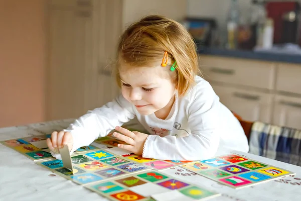 Adorable linda niña jugando juego de cartas imagen en casa o guardería. Feliz niño sano entrenando la memoria, pensando. Paso de desarrollo y educación del niño . — Foto de Stock
