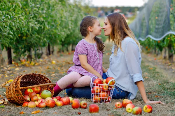Portrait de petite fille et belle mère aux pommes rouges dans un verger bio. Femme heureuse et fille enfant cueillant des fruits mûrs dans les arbres et s'amusant. Saison de récolte pour la famille. — Photo