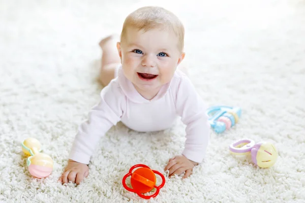 Cute baby playing with colorful pastel vintage rattle toy. New born child, little girl looking at the camera and crawling. Family, new life, childhood, beginning concept. Baby learning grab. — Stock Photo, Image