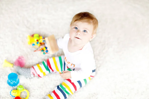 Adorável menina brincando com brinquedos educativos no berçário. Criança saudável feliz se divertindo com brinquedos diferentes coloridos em casa. Desenvolvimento do bebê e primeiros passos, aprendendo a jogar e agarrar. — Fotografia de Stock