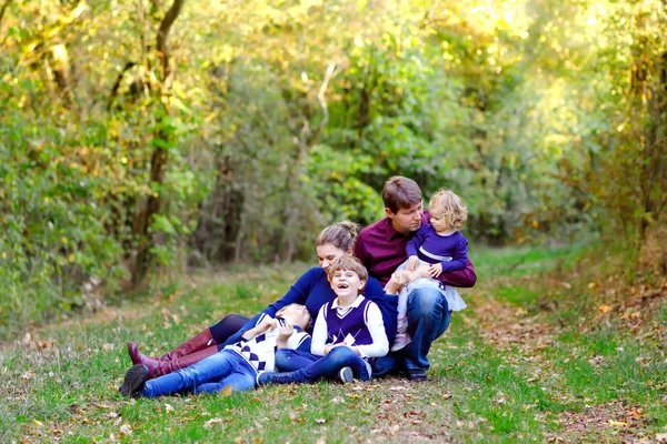 Porträtt av unga föräldrar med tre barn. Mor, far, två barn bröder pojkar och liten söt småbarn syster flicka har roligt tillsammans i höstskogen. Lycklig familj på fem — Stockfoto