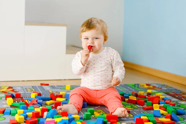 Eğitici oyuncaklarla oynayan sevimli bir kız bebek. Mutlu sağlıklı bir çocuk, evdeki renkli tahta bloklarla eğleniyor. Bebek öğrenme renkleri ve biçimleri — Stok fotoğraf