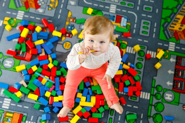 Eğitici oyuncaklarla oynayan sevimli bir kız bebek. Mutlu sağlıklı bir çocuk, evdeki renkli tahta bloklarla eğleniyor. Bebek öğrenme renkleri ve biçimleri — Stok fotoğraf