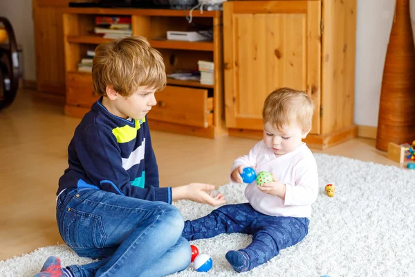 Menino pequeno feliz com a menina pequena bonito, irmã bonito. Irmãos. Irmão e bebê brincando juntos. Criança mais velha mostrando bebê fazendo pirâmide de madeira. Família e amor — Fotografia de Stock