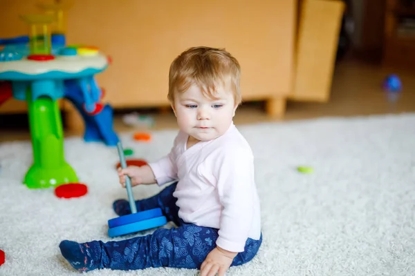 Nuttet baby pige leger med pædagogisk legetøj. Happy sundt barn har det sjovt med farverige forskellige træ legetøj derhjemme. Tidlig udvikling for børn med naturlegetøj. - Stock-foto