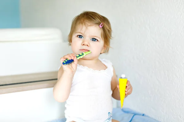 Niña sosteniendo cepillo de dientes y cepillándose los primeros dientes. Niño aprendiendo a limpiar los dientes de leche. Concepto de prevención, higiene y salud. Niño feliz en el baño — Foto de Stock
