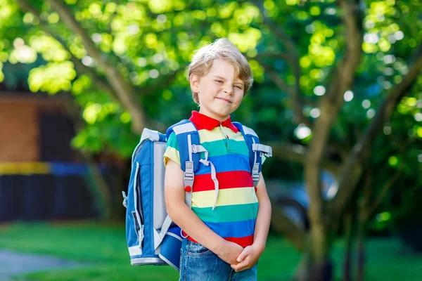 Glücklicher kleiner Junge in buntem Hemd und Rucksack oder Schulranzen an seinem ersten Schul- oder Kindergartentag. Kind an warmen, sonnigen Tagen im Freien, zurück zum Schulkonzept. Junge in bunter Uniform. — Stockfoto