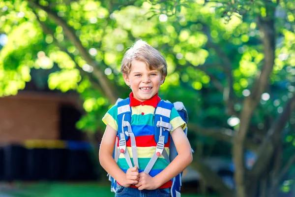 Ragazzino felice in camicia colorata e zaino o borsa il suo primo giorno di scuola o vivaio. Bambino all'aperto in una calda giornata di sole, torna al concetto di scuola. Ragazzo in uniforme colorata. — Foto Stock