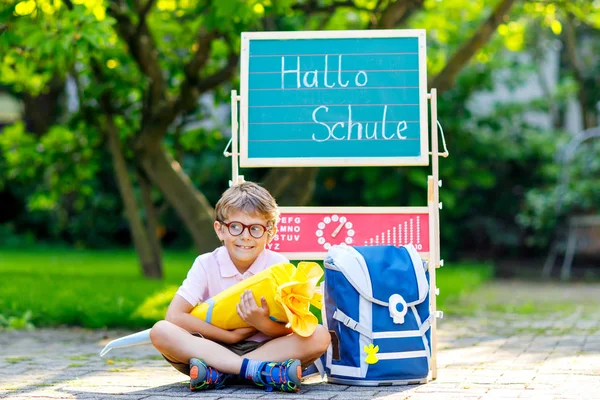 快乐的小男孩，戴着眼镜坐在桌旁，背包或背包。第一天上学的时候，带着德国传统书包锥的学童就叫Schultuete — 图库照片