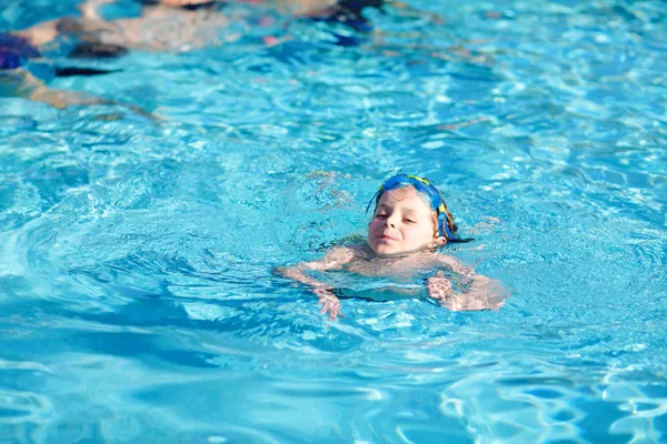 Маленький мальчик из детского сада делает соревнования по плаванию. Ребенок в очках для плавания достигает края бассейна. Ребенок веселится в бассейне. Активный счастливый ребенок выигрывает. спорт, активный отдых . — стоковое фото