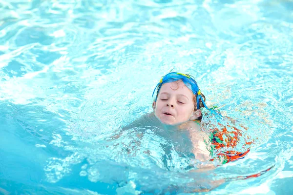 little preschool kid boy making swim competition sport. Kid with swimming goggles reaching edge of the pool . Child having fun in an swimming pool. Active happy child winning. sports, active leisure.