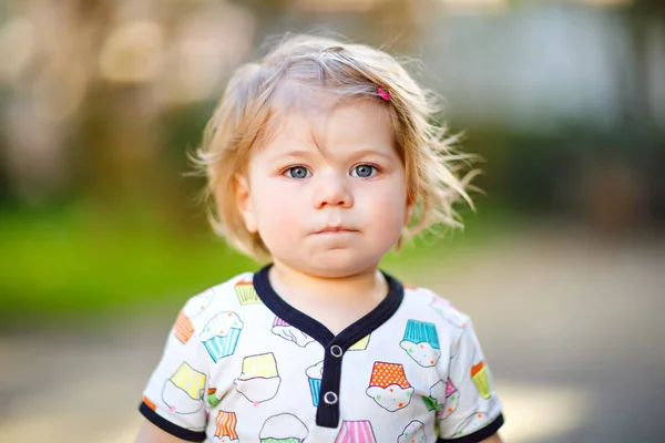 Porträtt av söt liten baby flicka i vårträdgård på solig dag. Vackra glada leende barn med blommande rosa magnoliaträd på bakgrund. Friskt barn njuter av vårsäsongen. — Stockfoto