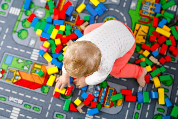 Eğitici oyuncaklarla oynayan sevimli bir kız bebek. Mutlu sağlıklı bir çocuk, evdeki renkli tahta bloklarla eğleniyor. Bebek öğrenme renkleri ve biçimleri — Stok fotoğraf