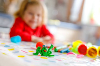 Sevimli sevimli küçük yürümeye başlayan çocuk kız renkli kil ile. Oyun ve oyuncak oyun hamuru oluşturma sağlıklı bir bebek. Modelleme kil kalıplama ve öğrenme küçük çocuk. Kil ile yapılan kurbağa odaklanmak