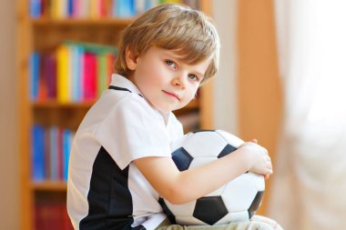 Futbol topu olan sarışın anaokulu çocuğu TV 'de futbol maçı izliyor. Komik, mutlu, ağlayan çocuk hayranı eğleniyor ve futbol takımını destekliyor. Şampiyonlar ve Dünya Kupası konsepti