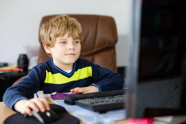 En lille dreng, der laver lektier på computer. Glædelig sund barn søger oplysninger på internettet. Ny medieuddannelse, barn, der ser læringslektioner på pc. Virtuelt klasseværelse . - Stock-foto