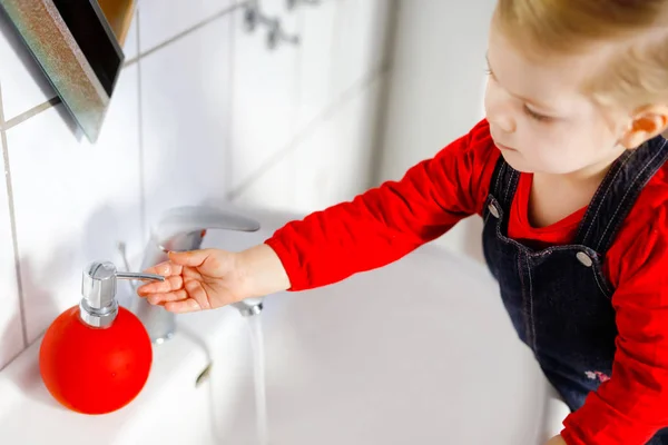 Küçük tatlı kız banyoda sabun ve suyla ellerini yıkıyor. Sevimli çocuk vücut parçalarını temizlemeyi öğreniyor. Sabah hijyen rutini. Evde ya da kreşte mutlu sağlıklı bir çocuk. — Stok fotoğraf