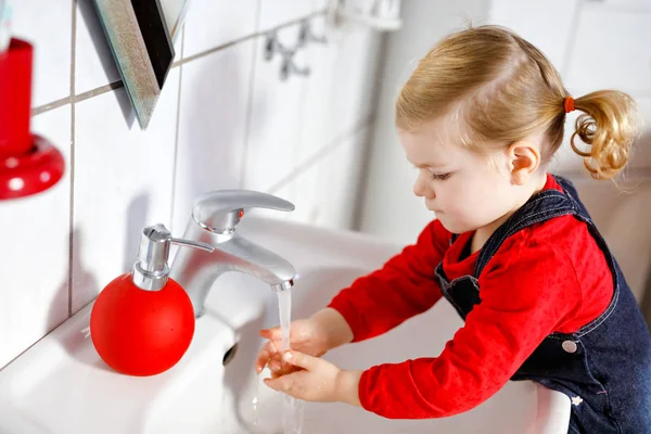 Söt liten småbarn flicka tvätta händerna med tvål och vatten i badrummet. Förtjusande barnuppfostran av kroppsdelar. Morgon hygien rutin. Glad frisk unge hemma eller på dagis. — Stockfoto