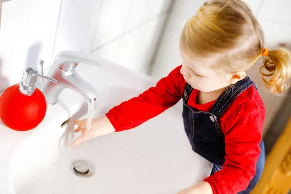 Schattig klein peuter meisje wassen handen met zeep en water in de badkamer. Schattig kind leren schoonmaken lichaamsdelen. Ochtendhygiëne. Gelukkig gezond kind thuis of in de kinderkamer. — Stockfoto