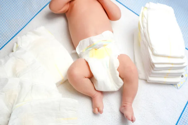 Feet of newborn baby on changing table with diapers. Cute little girl or boy two weeks old. Dry and healthy body and skin concept. Baby nursery. — Stock Photo, Image