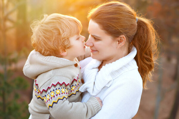 Mother and little son in park or forest, outdoors. Hugging and having fun together. Happy toddler boy and young mum, kid and woman playing