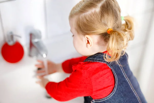 Aranyos kislány kezet mos szappannal és vízzel a fürdőszobában. Imádnivaló gyermek tanulás tisztító testrészek. Reggeli higiéniai rutin. Boldog egészséges gyereket otthon vagy gyerekszobában. — Stock Fotó