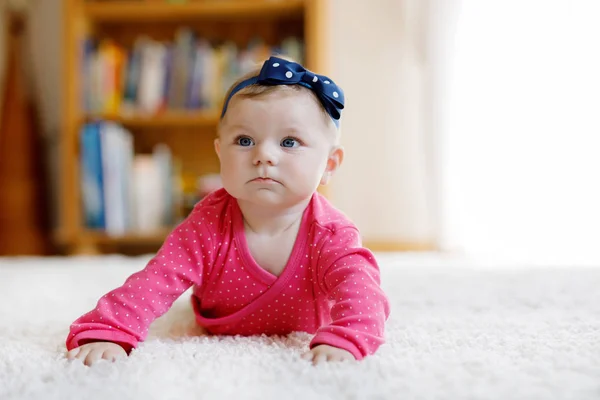 Bébé fille aux yeux bleus couché sur le ventre. Pépinière pour enfants. Textile et literie pour enfants. Joyeux nouveau-né. enfant avec bandeau . — Photo