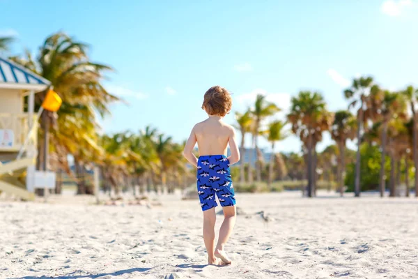 Sarışın küçük çocuk çocuk Miami beach, Key Biscayne üzerinde eğleniyor. Kumla oynayan ve okyanus yakın çalışan mutlu sağlıklı sevimli bir çocuk. Avuç içi, güvenlik ev ve beyaz kum — Stok fotoğraf
