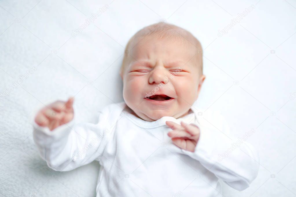 Crying newborn baby on changing table. Cute little girl or boy two weeks old. Dry and healthy body and skin concept. Baby nursery.
