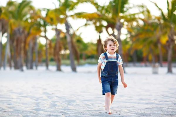 Uroczy, aktywny chłopiec bawiący się na plaży w Miami, Key Biscayne. Happy cute dziecko relaks, gry z piaskiem i korzystających słoneczny ciepły dzień w pobliżu palm i oceanu — Zdjęcie stockowe