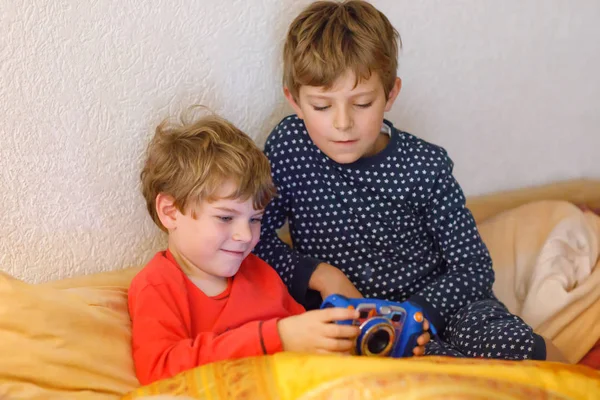 Dois pré-escolares ou escolares meninos, irmãos e irmãos se divertindo depois do dia da escola jogando videogame em casa e tirando fotos com câmera de brinquedo. Melhores amigos, gêmeos de pijama ou roupa de noite — Fotografia de Stock