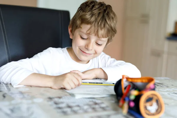 Vermoeide kleine jongen die thuis huiswerk maakt op de ochtend voor de school begint. Klein kind aan het sporten, binnen. Basisschool en onderwijs. — Stockfoto