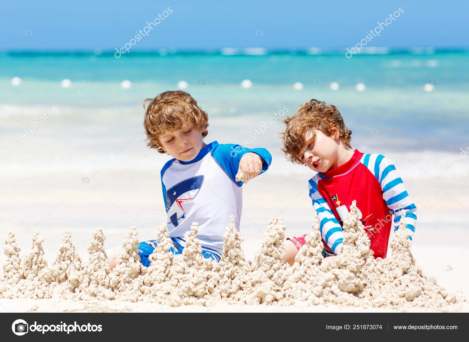 garçons heureux faisant un château de sable sur la plage