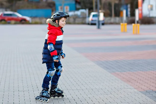 Leuke school jongen jongen schaatsen met rollen in de stad. Gelukkig gezond kind in bescherming veiligheid kleding schaatsen met rollen. Actieve schooljongen maken van sport en leren om te skaten op inline skater. — Stockfoto