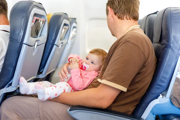 Padre che tiene in braccio sua figlia durante il volo in aereo in vacanza — Foto Stock