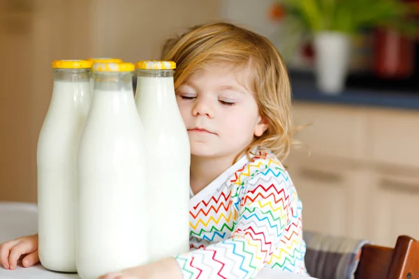 Adorabile bambina che beve latte vaccino per colazione. Carina la figlioletta con tanti biberon. Bambino sano che ha il latte come fonte di calcio sano. Bambino a casa o asilo nido al mattino. — Foto Stock