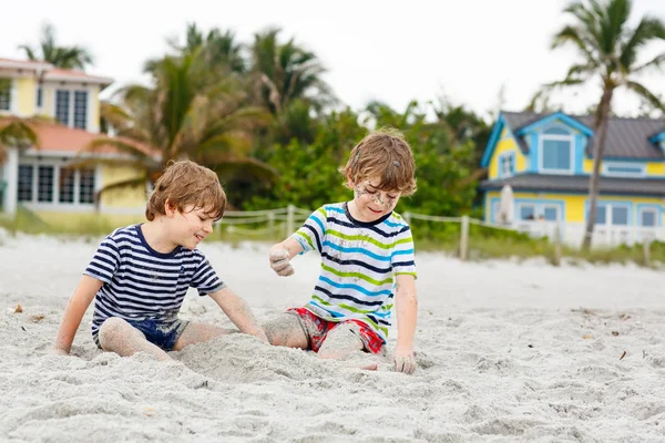 İki küçük çocuklar dostluk kavramı eğleniyor tropik sahilde oynarken, mutlu arkadaşlarım çocuğu. Kardeş kardeş, İkizler aile arka plan üzerinde avuç içi ile bak. Florida aile tatiller. — Stok fotoğraf