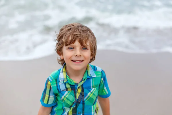 可爱的活泼的小男孩在德国北海海滩乐趣。快乐可爱的孩子放松, 玩和享受暴风雨温暖的一天附近的棕榈和海洋。在滑稽美丽的脸上的沙子的孩子. — 图库照片