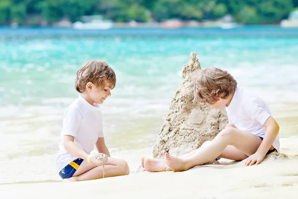 Два мало діти веселяться із пісок замок на тропічні пляжі Сейшельських островів. дітей, що грають разом на свою відпустку — стокове фото
