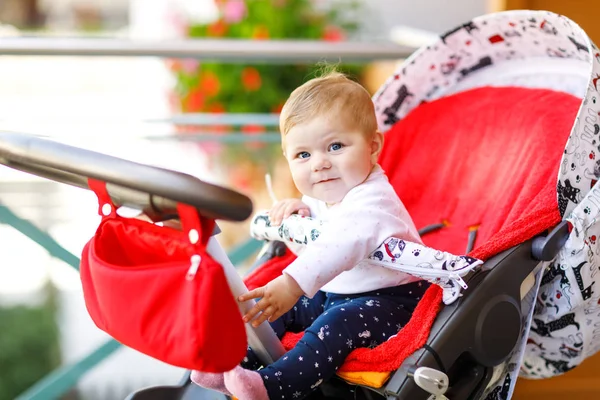 Linda niñita hermosa sentada en el cochecito o cochecito y esperando a mamá. Feliz niño sonriente con ojos azules. Adorable hija bebé va a dar un paseo —  Fotos de Stock