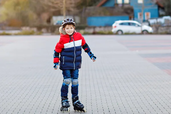 Leuke school jongen jongen schaatsen met rollen in de stad. Gelukkig gezond kind in bescherming veiligheid kleding schaatsen met rollen. Actieve schooljongen maken van sport en leren om te skaten op inline skater. — Stockfoto