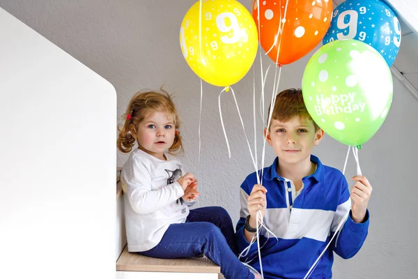 Portrait de garçon enfant heureux et mignon petite fille tout-petit avec bouquet sur des ballons à air coloré sur anniversaire. Souriant heureux écolier et soeur s'amuser, célébrer l'anniversaire. Fête de famille — Photo