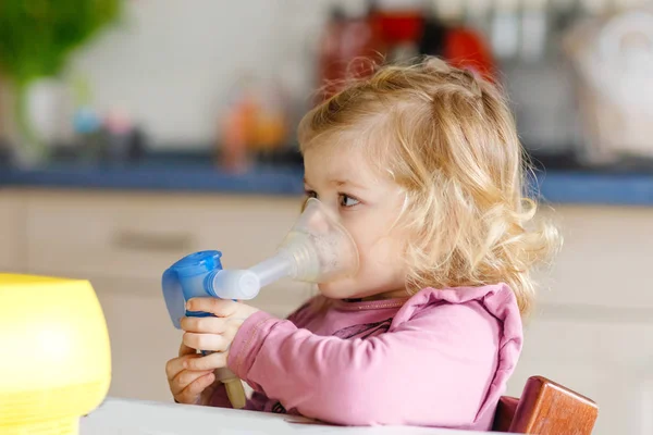Κοριτσάκι που κάνει εισπνοή με νεφελοποιητή στο σπίτι. Πατέρας ή μητέρα βοηθώντας και κρατώντας τη συσκευή. Παιδί που έχει γρίπη, βήχα και βρογχίτιδα. εισπνευστήρας εισπνεόμενου ατμού — Φωτογραφία Αρχείου