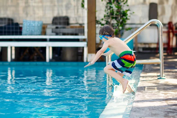 Piccolo bambino felice in età prescolare che salta in acqua in piscina. Bambino che si diverte in piscina . — Foto Stock