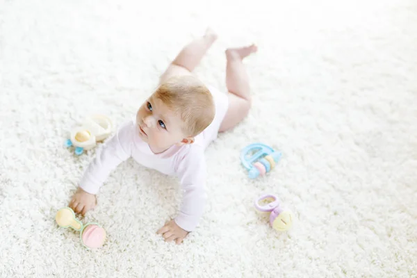 Lindo bebé jugando con colorido pastel vintage sonajero juguete. Niño recién nacido, niña mirando a la cámara y gateando. Familia, nueva vida, infancia, concepto inicial. Bebé aprendizaje agarrar. —  Fotos de Stock