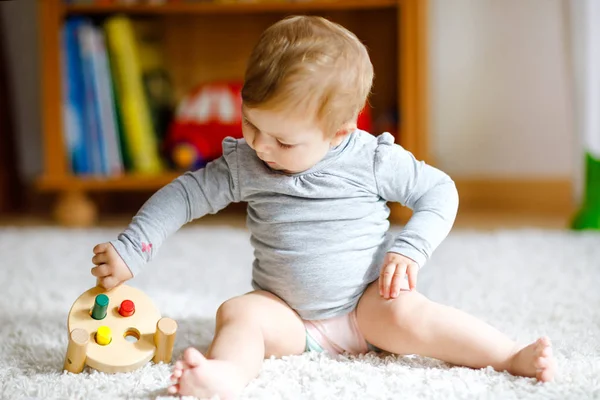 Adorável menina brincando com brinquedos educativos. Criança saudável feliz se divertindo com brinquedo de madeira diferente colorido em casa. Desenvolvimento precoce para crianças com brinquedo da natureza. — Fotografia de Stock