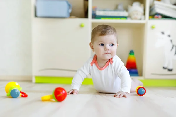 Aranyos boldog mosolygó baba játék a játék, színes csörgő. Új született gyermek, kislány, tanulás, másznak. Család, új élet, gyermekkori, elején koncepció. Baba tanulási megragad fa tömb. — Stock Fotó